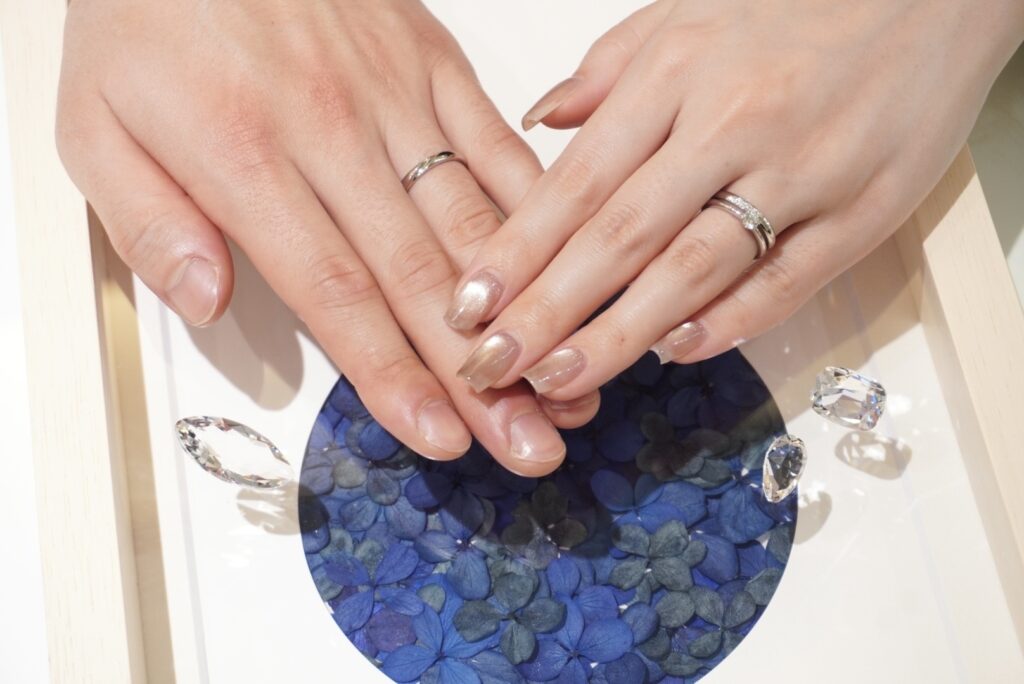 ロイヤル・アッシャーの婚約指輪と結婚指輪を着けたカップルの手元