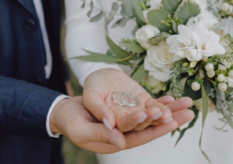 結婚指輪を持つカップルの手