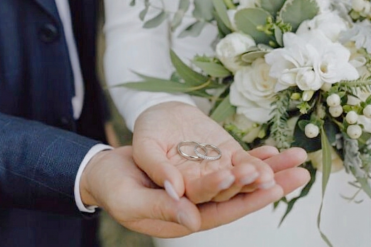 結婚指輪を持つカップルの手