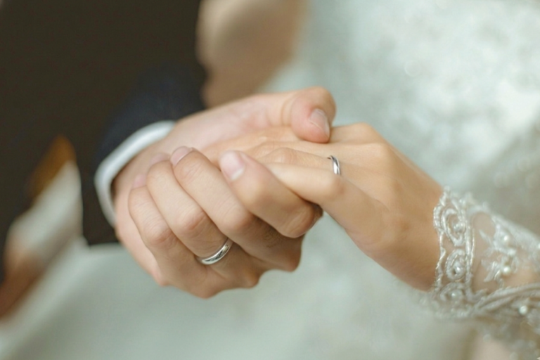 結婚指輪を着けたカップルの手