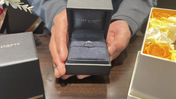 ラザールダイヤモンドの婚約指輪の入ったケースを持つ男性