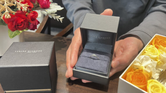 ラザールダイヤモンドの婚約指輪の入ったケースを持つ男性