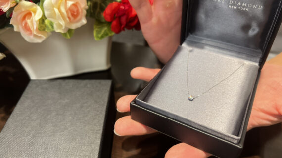 ラザールダイヤモンドの婚約ネックレスが入ったケースを持つ男性