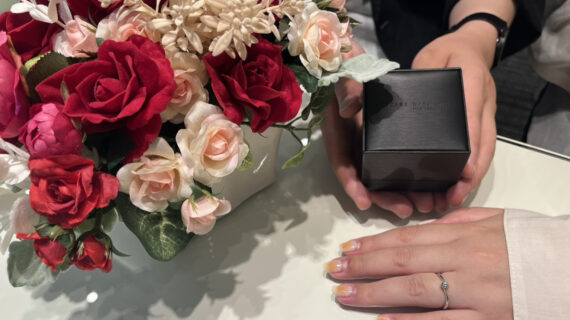 ラザールダイヤモンドの婚約指輪を着けた女性とケースを持つ男性