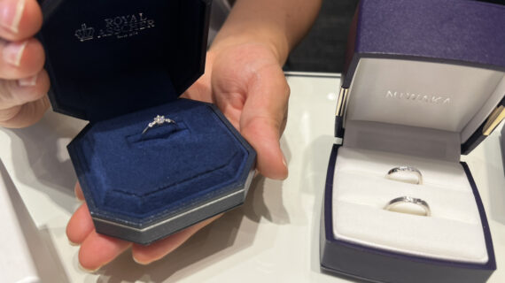 ロイヤル・アッシャーの婚約指輪が入ったケースを持つ男性とNIWAKA（ニワカ）の結婚指輪