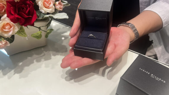 ラザールダイヤモンドの婚約指輪が入ったケースを持つ男性