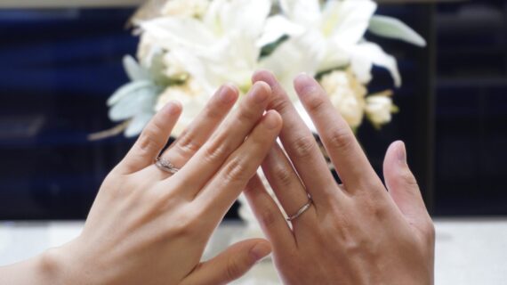 ロイヤル・アッシャーの婚約指輪と結婚指輪を着けたカップルの手元