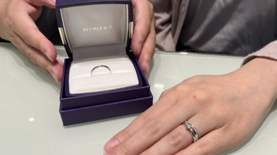 NIWAKA(ニワカ)の婚約指輪と結婚指輪を着けた女性と結婚指輪のケースを持つ男性の手元