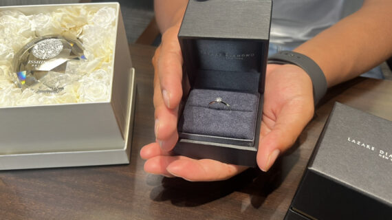 ラザールダイヤモンドの婚約指輪が入ったケースを持つ男性の手元