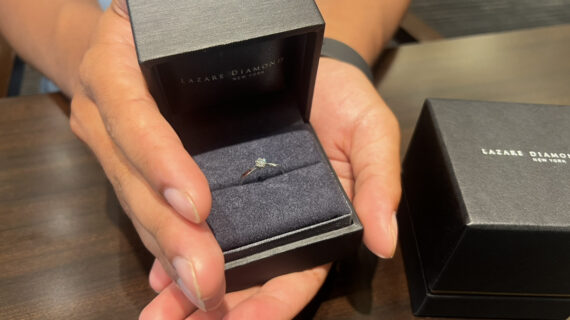 ラザールダイヤモンドの婚約指輪が入ったケースを持つ男性の手元