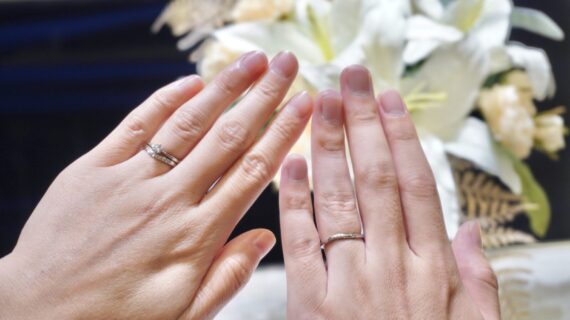 ロイヤル・アッシャーの婚約指輪と結婚指輪を着けたカップルの手元