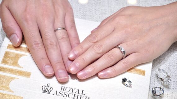 ロイヤル・アッシャーの婚約指輪と結婚指輪をつけたカップルの手元