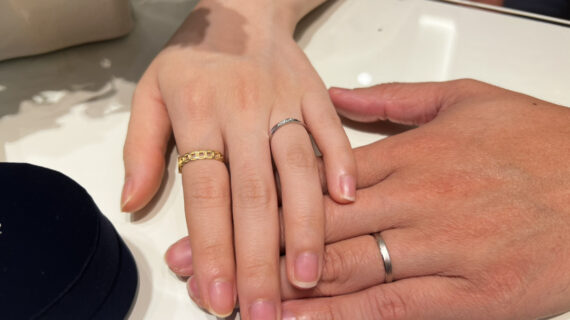 ノクルの結婚指輪を着けた男性とサムシングブルーの結婚指輪を着けた女性の手元
