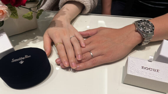 ノクルの結婚指輪を着けた男性とサムシングブルーの結婚指輪を着けた女性の手元