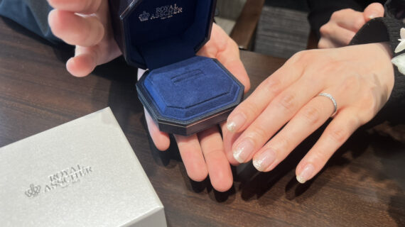 ロイヤル・アッシャーの結婚指輪を着けた女性の手元と箱を持つ男性の手元
