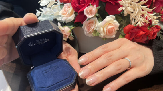 ロイヤル・アッシャーの結婚指輪を着けた女性の手元と箱を持つ男性の手元