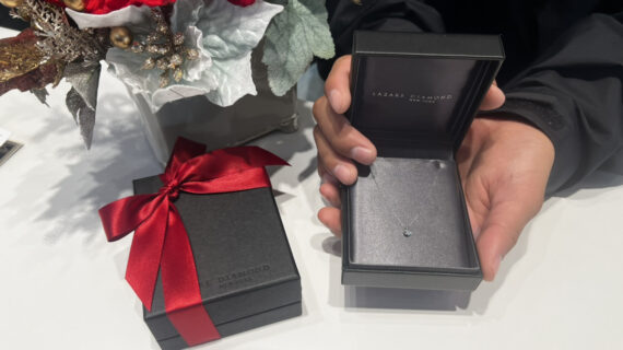 ラザールダイヤモンドの婚約ネックレスの入ったケースを持つ男性の手元