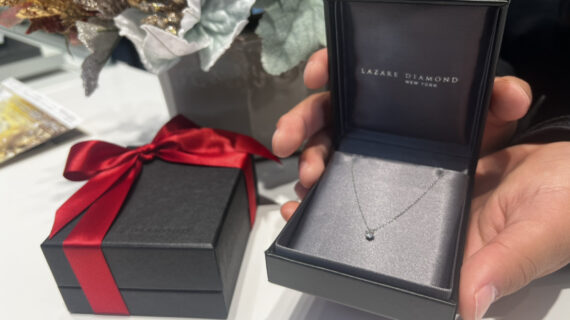 ラザールダイヤモンドの婚約ネックレスの入ったケースを持つ男性の手元