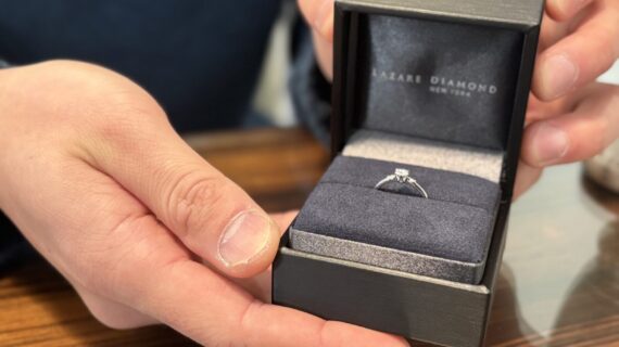 ラザールダイヤモンドの婚約指輪が入ったケースを開ける男性の手元の画像。