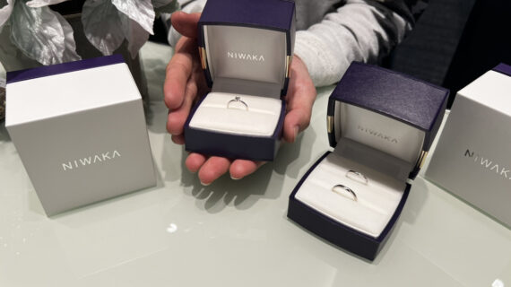 NIWAKA（ニワカ）の婚約指輪が入ったケースを持つ男性の手元とNIWAKA（ニワカ）の結婚指輪が入ったケース