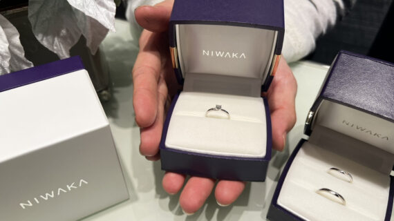 NIWAKA（ニワカ）の婚約指輪が入ったケースを持つ男性の手元とNIWAKA（ニワカ）の結婚指輪が入ったケース