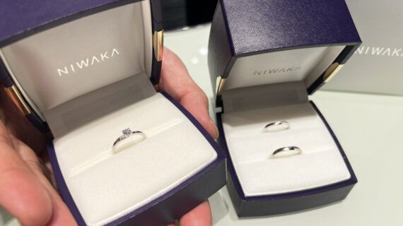 NIWAKA（ニワカ）の婚約指輪が入ったケースを持つ男性の手元とNIWAKA（ニワカ）の結婚指輪が入ったケース