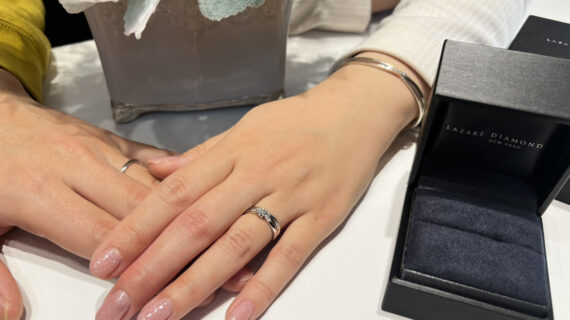 ラザールダイヤモンドの婚約指輪と結婚指輪を着けた女性と結婚指輪を着けた男性の手元