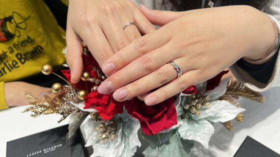 ラザールダイヤモンドの婚約指輪と結婚指輪を着けた女性と結婚指輪を着けた男性の手元