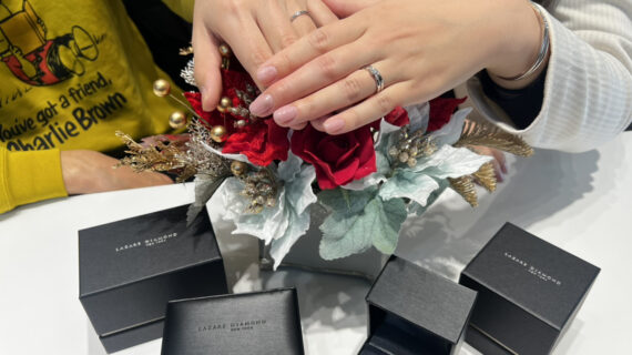 ラザールダイヤモンドの婚約指輪と結婚指輪を着けた女性と結婚指輪を着けた男性の手元