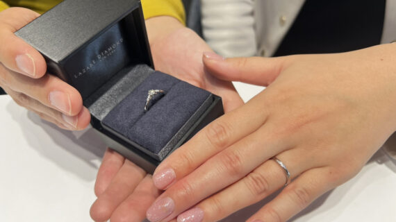 婚約指輪が入ったケースを持つ男性の手元と結婚指輪を着けた女性の手元