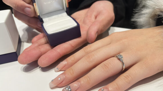 NIWAKA（ニワカ）の婚約指輪を着けた女性の手元とケースを持つ男性の手元
