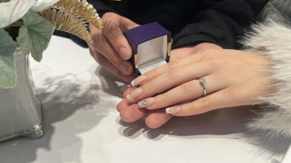NIWAKA（ニワカ）の婚約指輪を着けた女性の手元とケースを持つ男性の手元