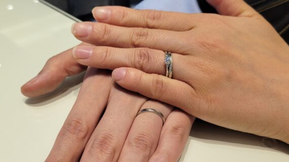 サムシングブルーの婚約指輪と結婚指輪を着けたカップルの手元