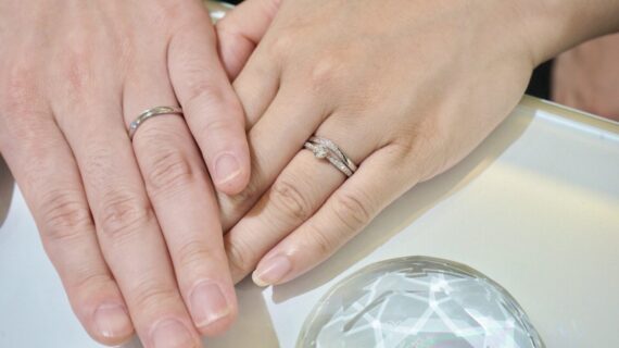 ロイヤル・アッシャーの婚約指輪とモニッケンダムの結婚指輪を着用したカップルの手元