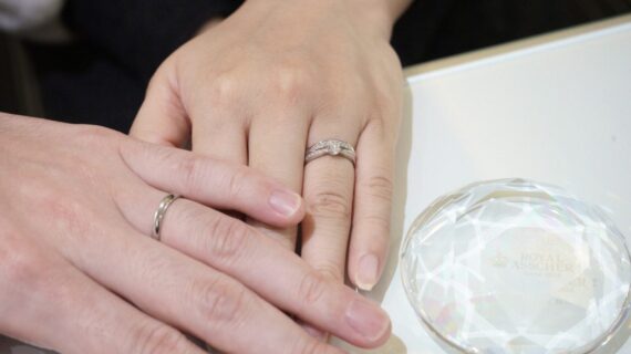 ロイヤル・アッシャーの婚約指輪とモニッケンダムの結婚指輪を着用したカップルの手元
