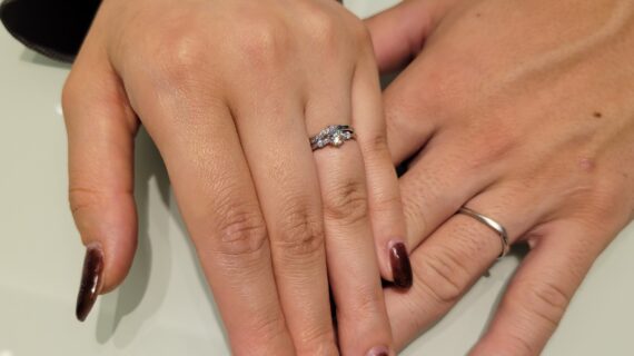 ロイヤル・アッシャーの婚約指輪と、カフェリングの結婚指輪を着けたカップルの手元