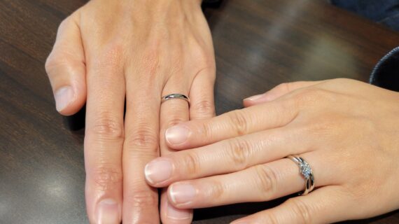 アイスブルーレーベルの婚約指輪と結婚指輪を着けたカップルの手元